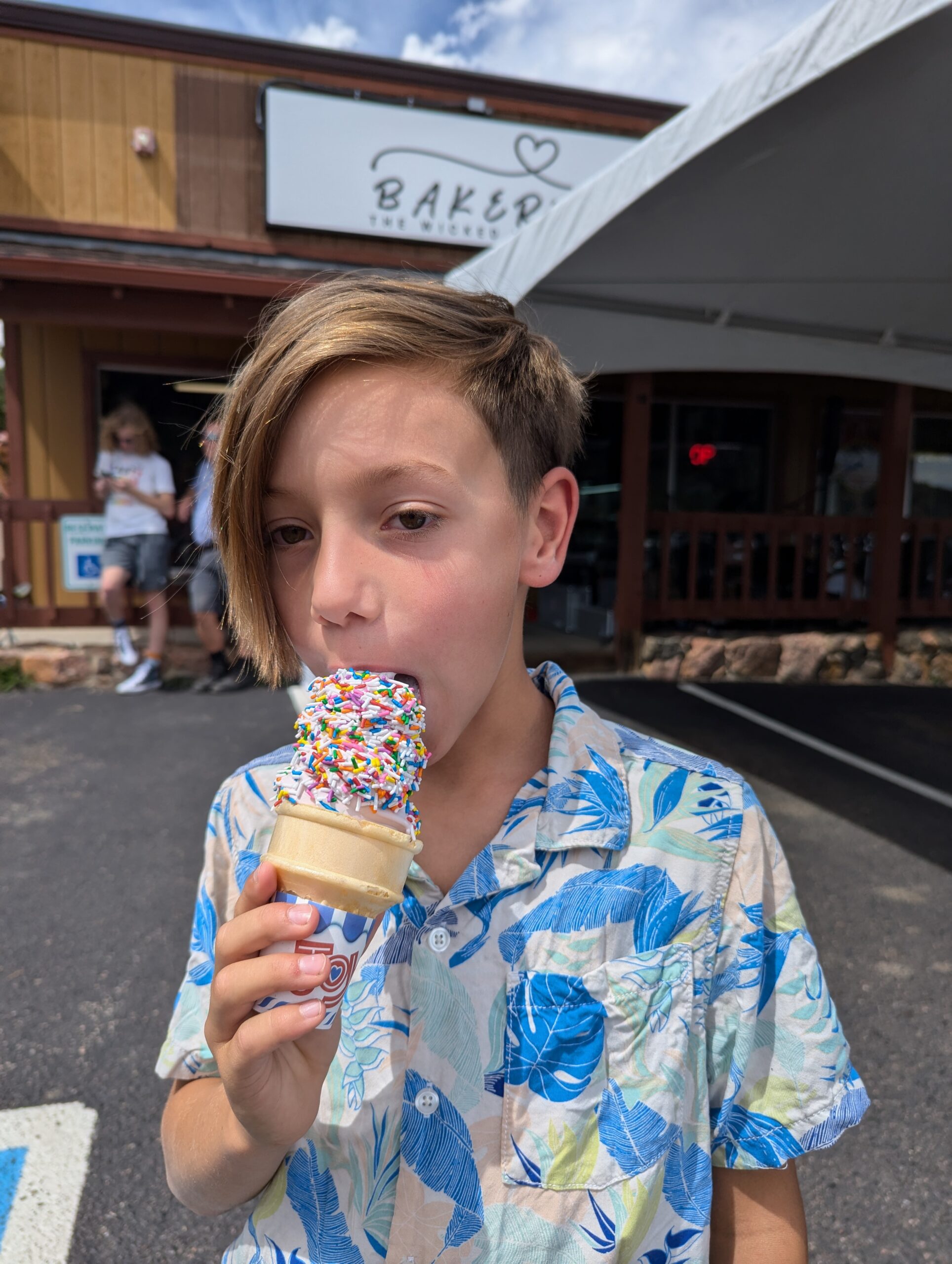 A young boy happily eats Ripple Soft Ice Cream covered in colorful sprinkles.