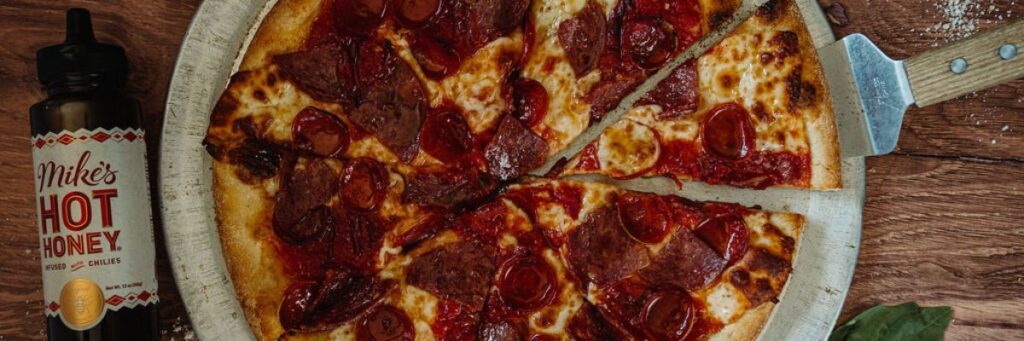 Hot Honey, sausage and pepperoni pizza wth Mike's Hot Honey bottle